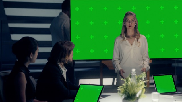 Mockup of Corporate Meeting Room: Professional Female Entrepreneur delivers a Business Pitch to Clients and Partners on a Chroma Green Screen Monitor with Trackers. Shot on ARRI ALEXA Mini UHD Camera