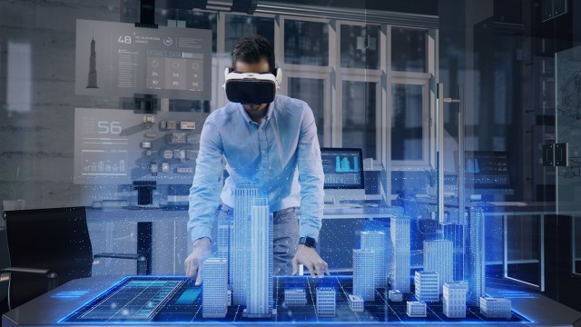 Professional Male Architect wearing Augmented Reality Headset makes gestures and redesigns 3D City Model. 