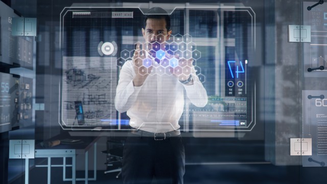 Successful Businessman works on large Transparent Interactive Window Touchscreen in his office.