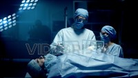Professional Surgeon and Assistant Analyze Patient Lung Diagnosis Data on Transparent Tablets During Surgery. Modern Hospital Operating Room. Shot on RED Epic-W Helium Camera.