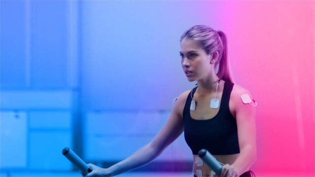 In Science High-Tech Sports Lab Beautiful Athlete Woman walks on treadmill using electrodes attached to her body. ECG and Holographic Data Overlay. Slow Motion. Shot on ARRI ALEXA Mini UHD Camera.