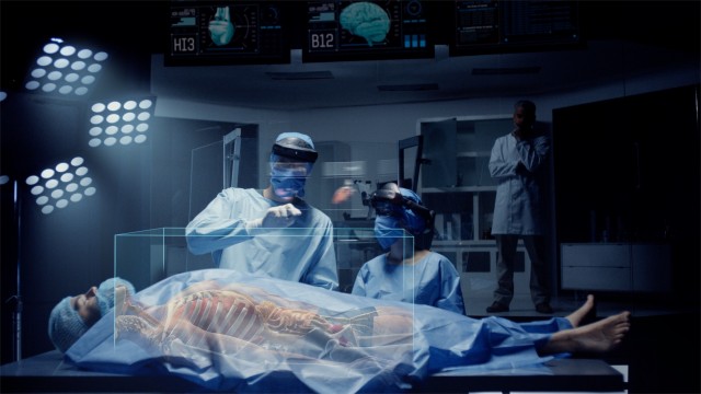 Team of Medical Surgeons use Augmented Holographic Technology to examine Patient. Nurse uses Hand Gestures to show the Organs, Bones and Full Anatomy of the Body of a Male Patient. Shot on RED Epic W.