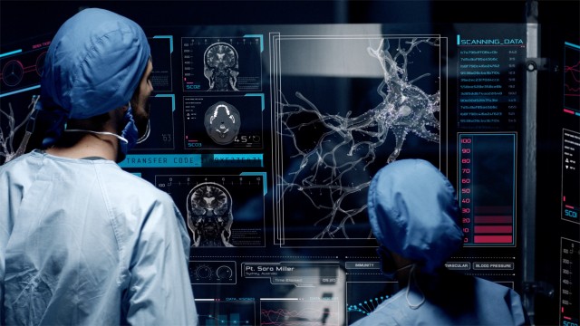 Professional doctors analyzing patient's medical MRI diagnosis by checking on a large glass screen with futuristic holograms. Concept of: medicine, doctors, future, holographic, brain scan