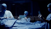 Team of Medical Surgeons use Futuristic Holographic Touchscreen Tablets to Examine Patient during Medical Procedure. Transparent Screens showing ECG and Medical Data Activity. Shot on RED Epic W.