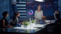 Female executive talks to board of directors and investors using a digital interactive monitor for presentation with purple and blue elements.