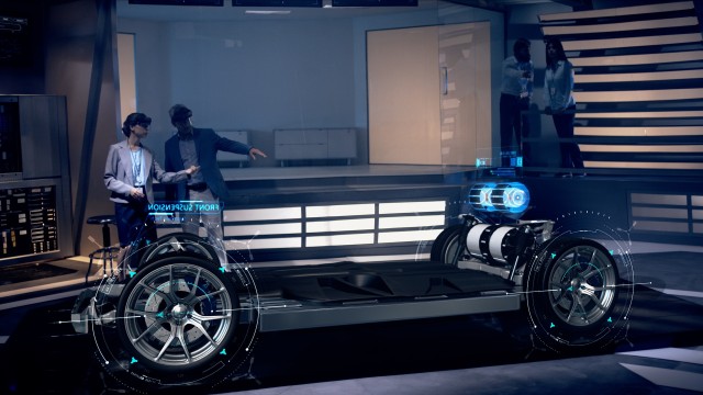 Female Engineer shows Electric Car Design Features to Client while wearing Holographic Headsets inside High-tech Industrial Facility. Concept of Augmented Reality. Shot on RED Epic W Helium 8K Camera.