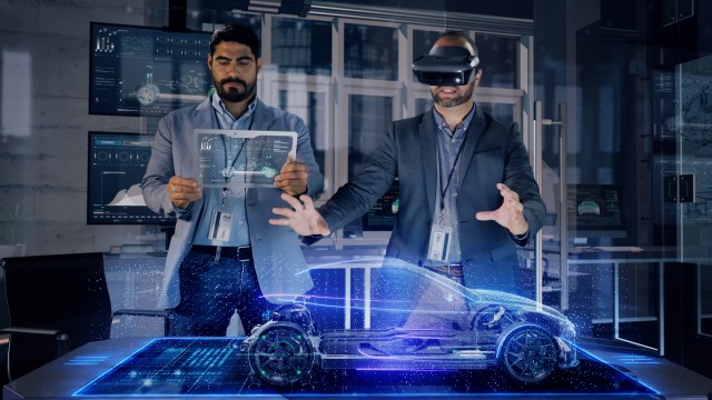 Male Automotive Designers in Suit Wearing AR Headset and Transparent Tablet Analyzing 3D Electric Concept Car Model. 
