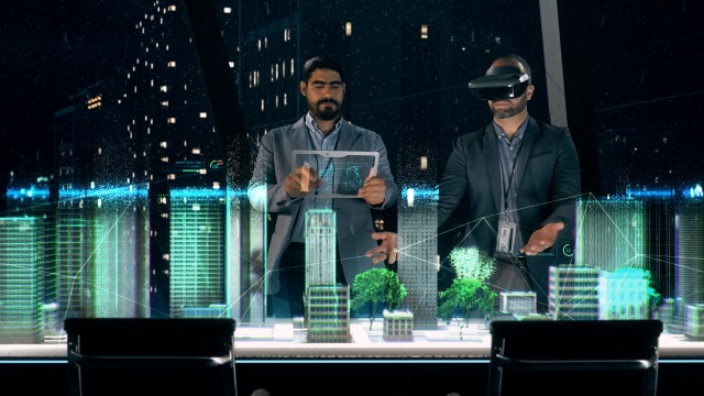 In the Near Future: Professional Designer in Suit wearing AR Headset presenting Architecture Project to Partner.